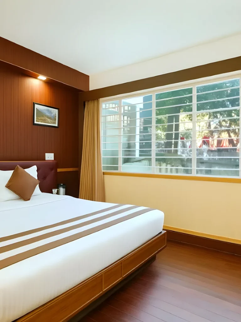 Guest room with a burgundy headboard, dark wood flooring and a window view at Hotel Apsara, Darjeeling